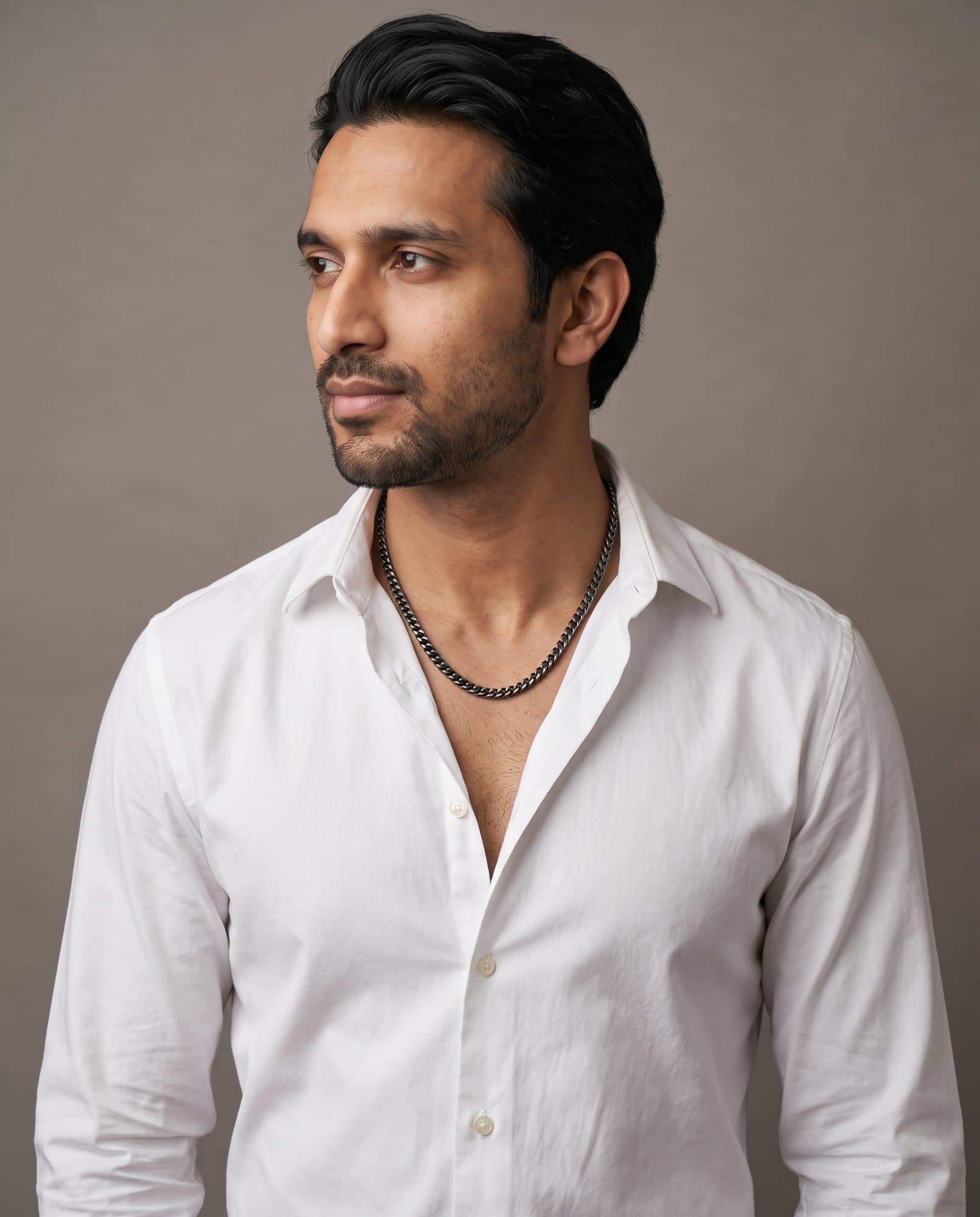 A man in an open white shirt, the Abydos Franco Chain resting on his collarbones.
