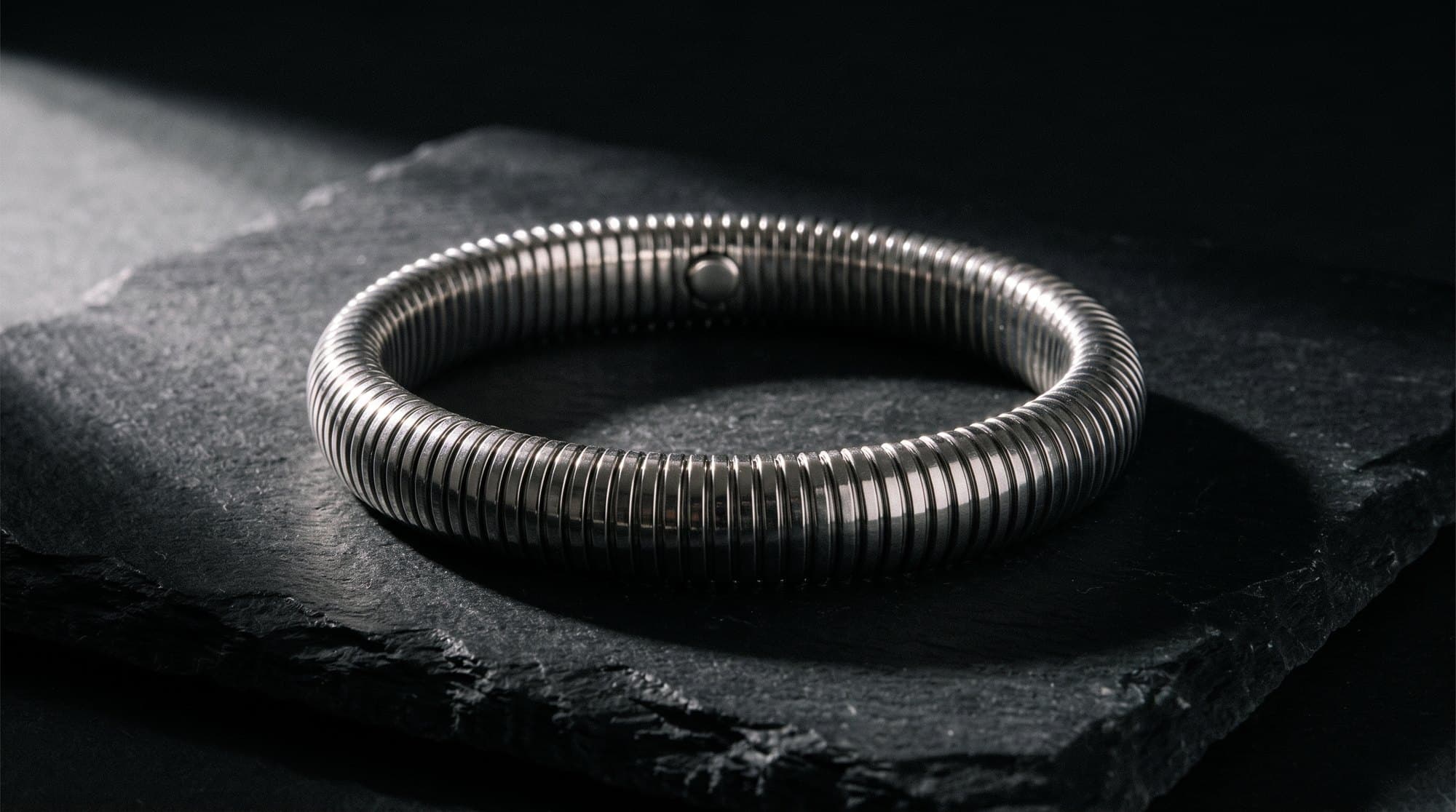 The Coil Bangle on black slate under a single raking light.