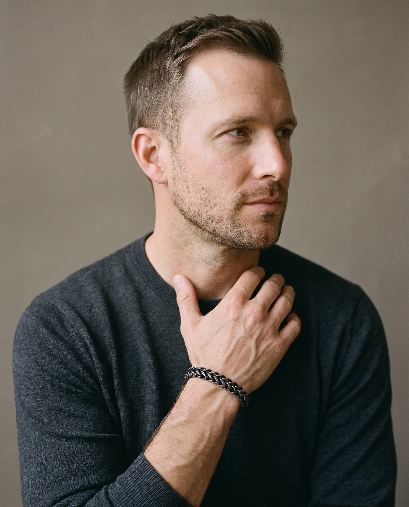 A man in a charcoal knit with his hand at his collarbone, the Franco Cord Chain on his wrist.