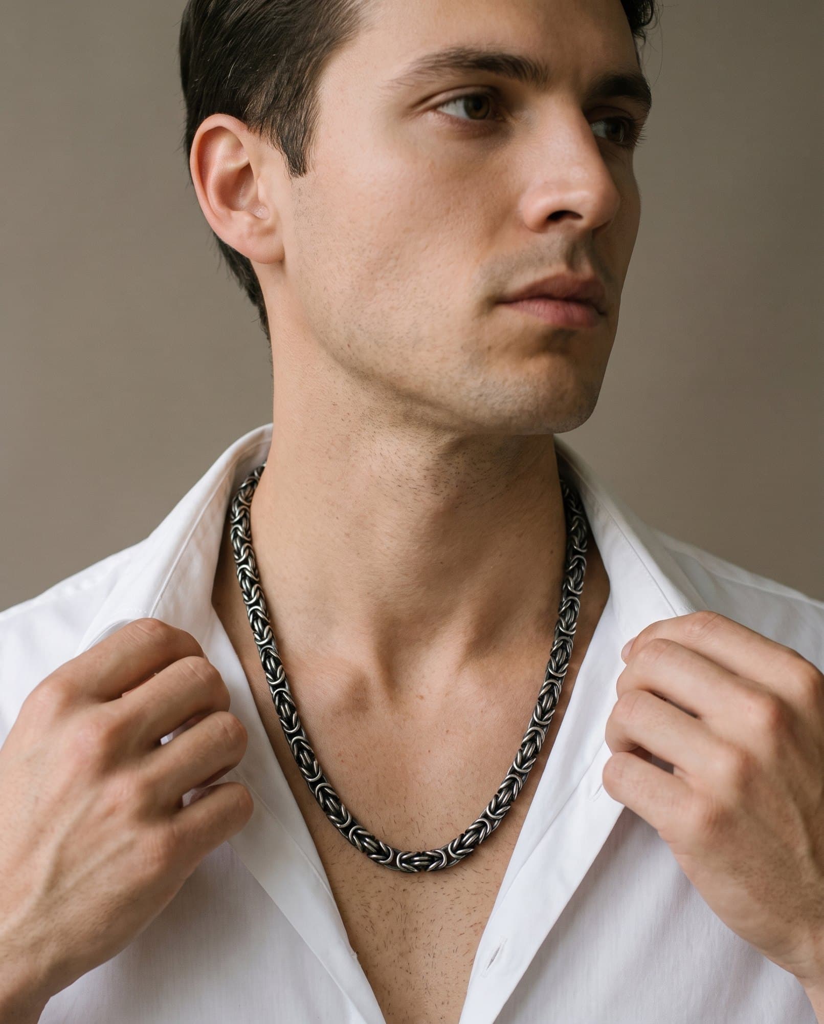 A man in an open white shirt, the Karnak Byzantine Chain resting on his collarbones.