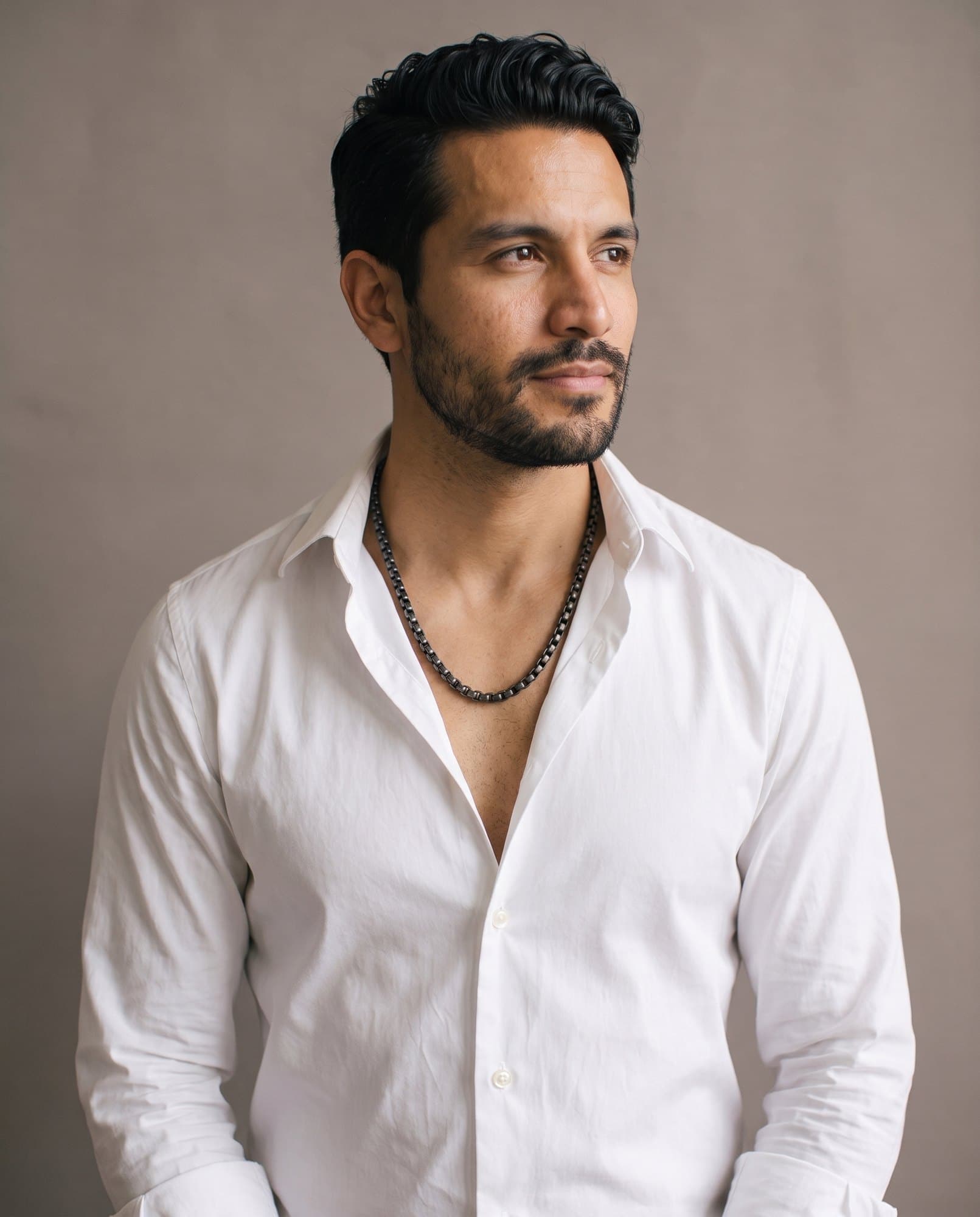 A man in an open white shirt, the Obelisk Box Chain resting on his collarbones.
