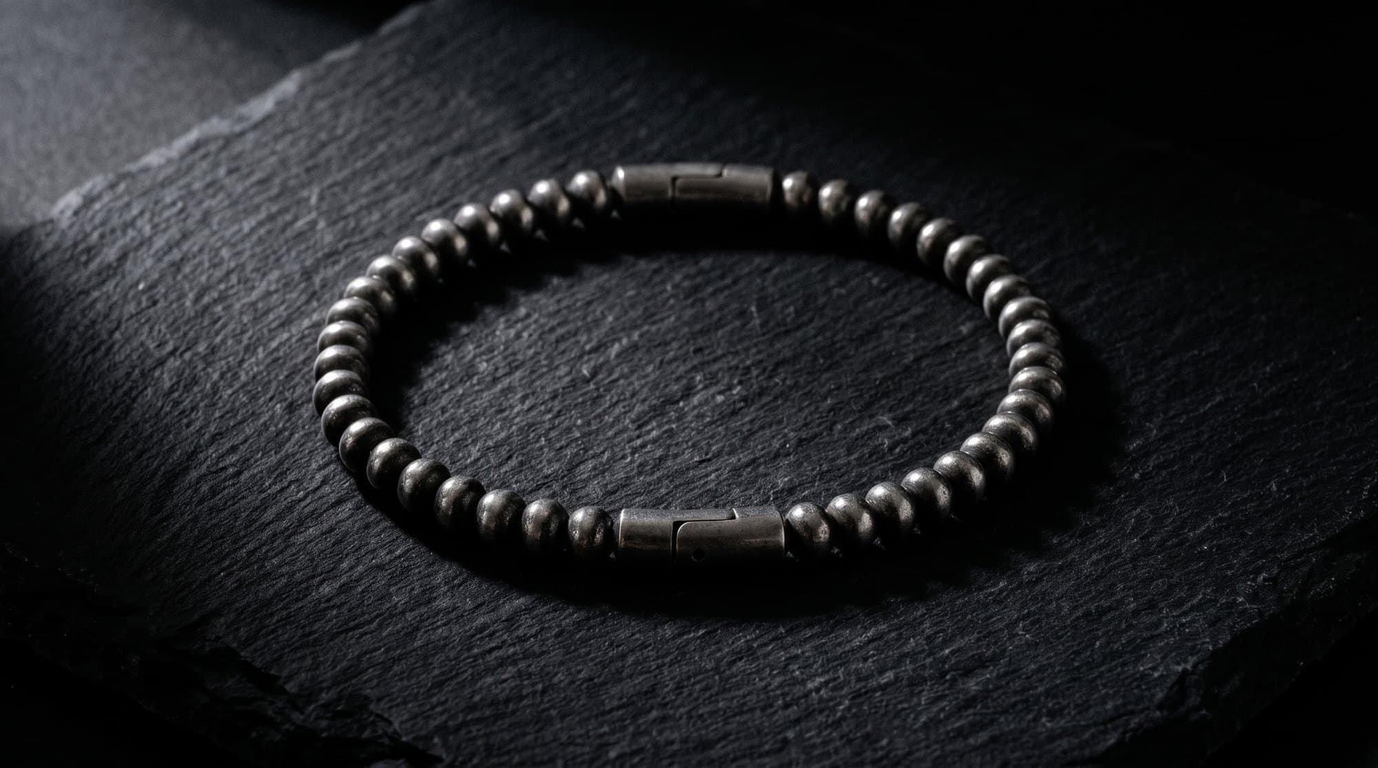 The Rondel Bead Chain on black slate under a single raking light.