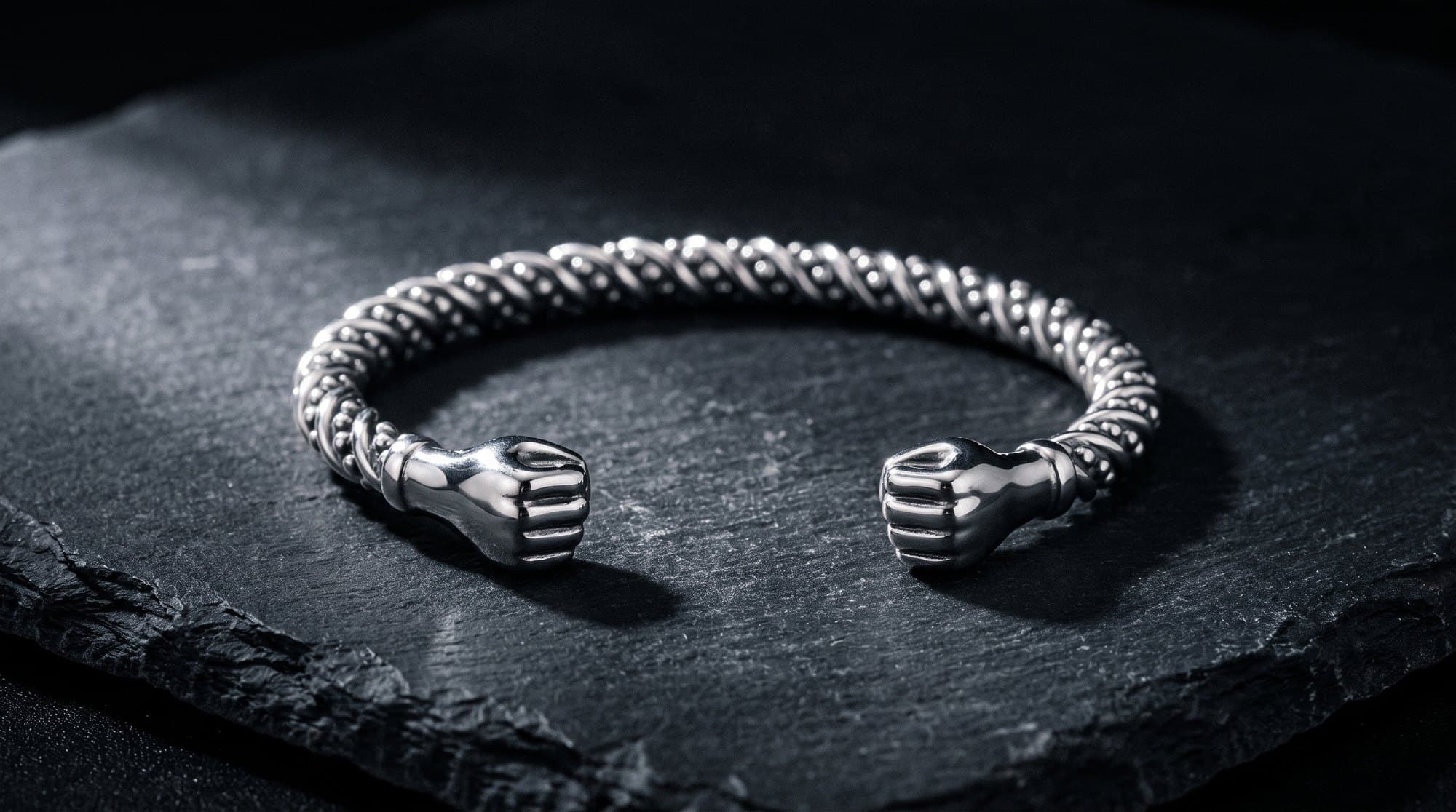 The Sovereign Fist Cuff on black slate under a single raking light.