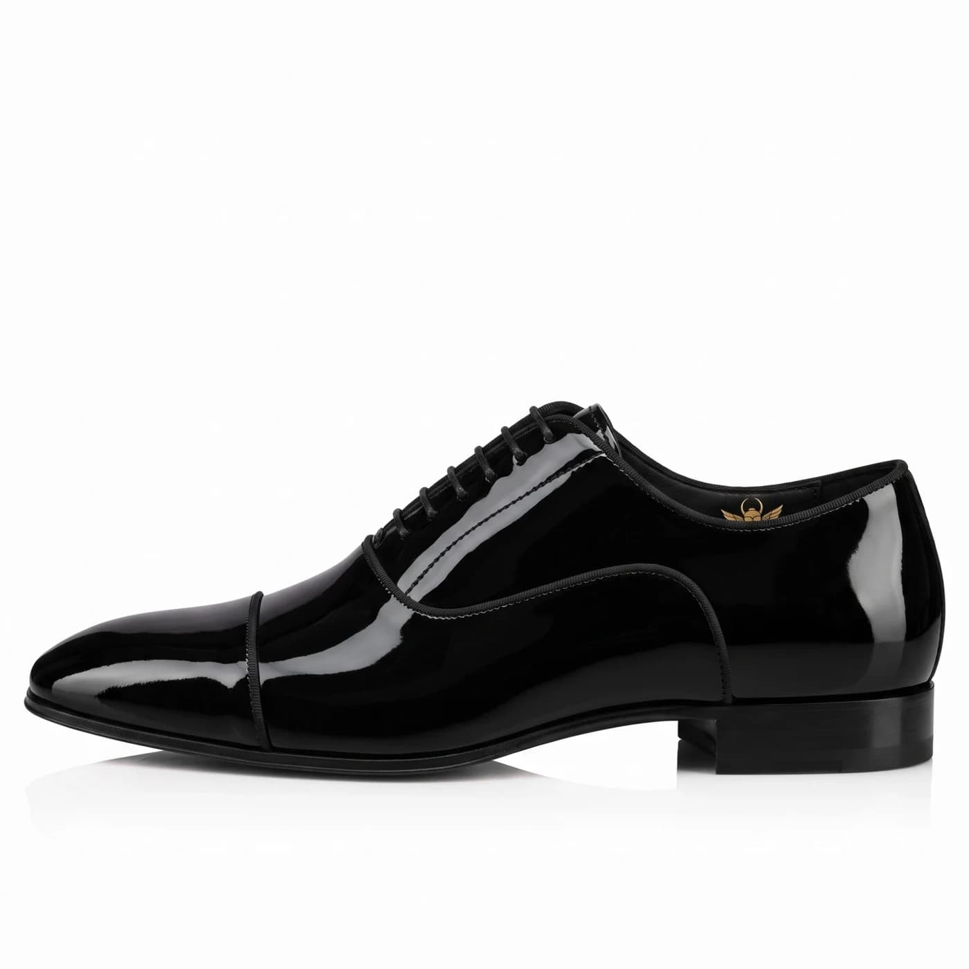 Black patent leather cap toe oxford in side profile, black cloth piping along the edges, the Malik Alexander scarab in gold inside