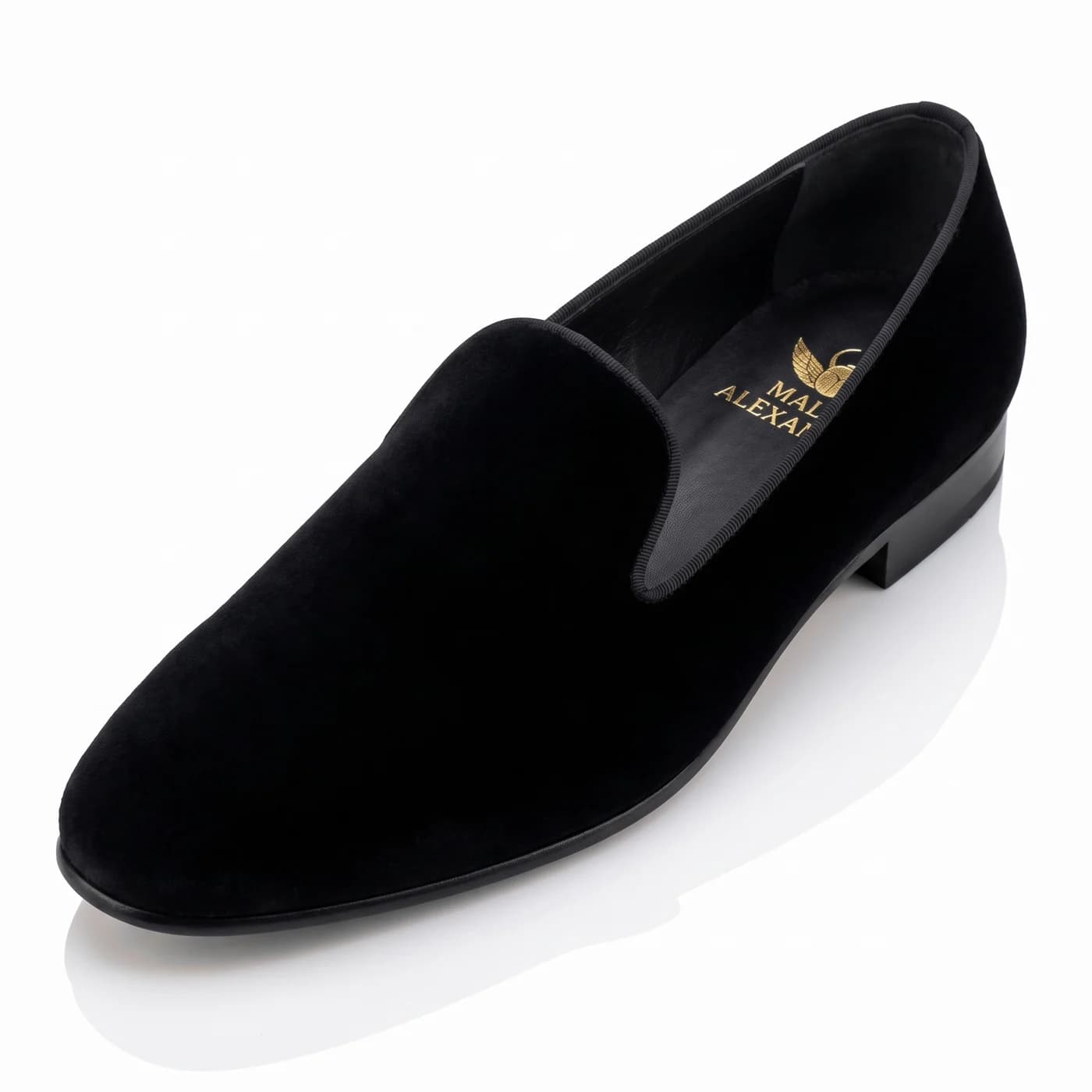 Black velvet smoking slipper seen from high at an angle, the Malik Alexander logo in gold on the black insole