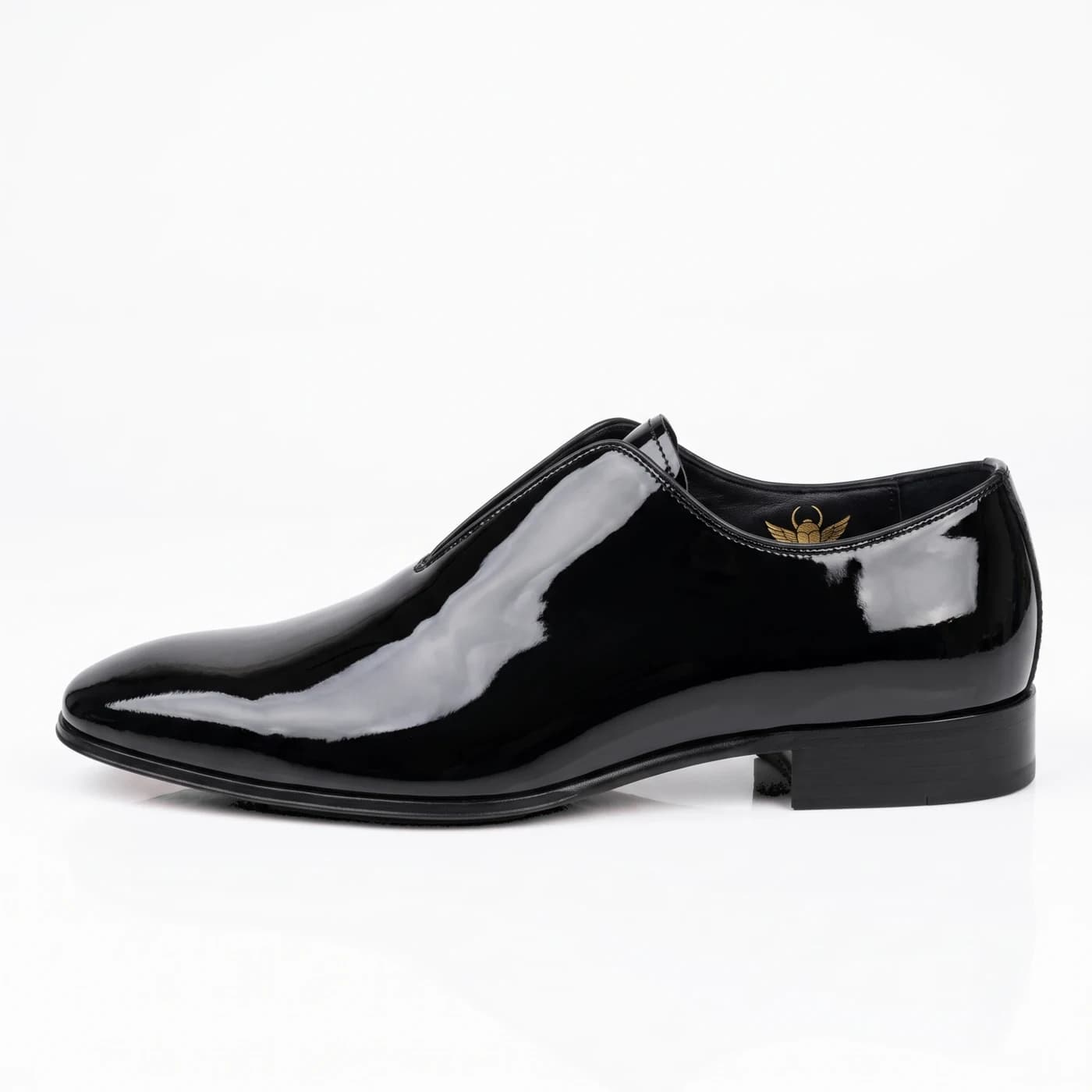 Black patent leather slip-on in side profile with a split instep, a low stacked heel and the gold scarab inside
