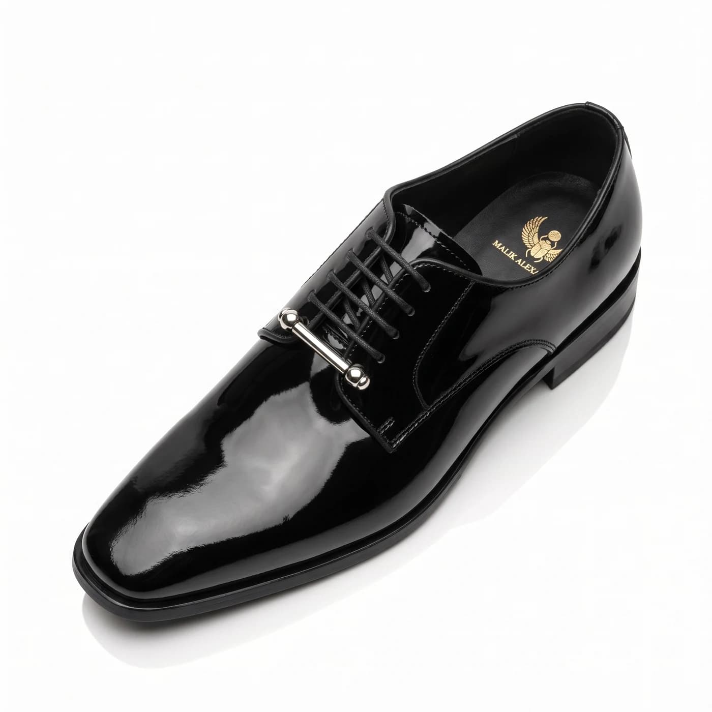 Black patent leather derby from above at an angle, the silver bar at the throat and the Malik Alexander logo in gold on the insole